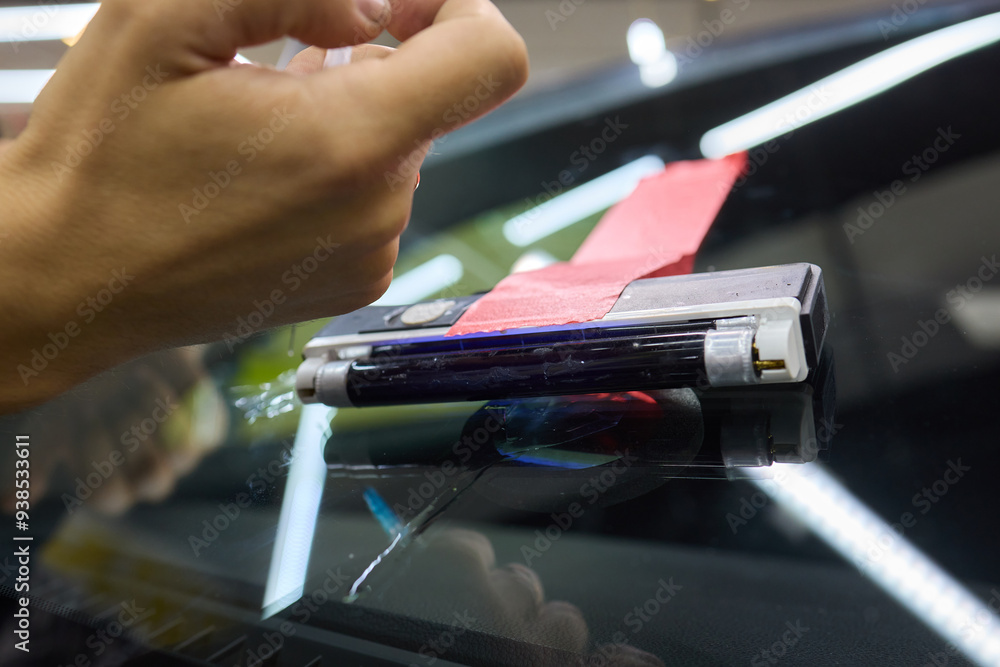 Poster expertly repairing a windshield utilizing precision tools in an auto service workshop
