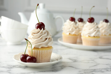 Delicious cupcakes with cream and cherries on white marble table