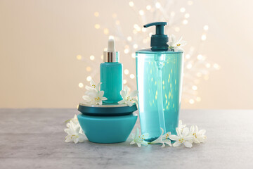 Cosmetic products and beautiful jasmine flowers on grey table