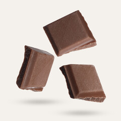 Pieces of sweet chocolate falling on beige background