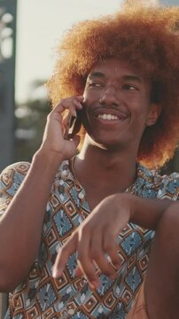 Happy curly-haired guy relaxing against the backdrop oof a yachts and palm trees 