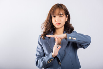 Closeup portrait young business woman wearing a suit smiling making time out gesture with hands...