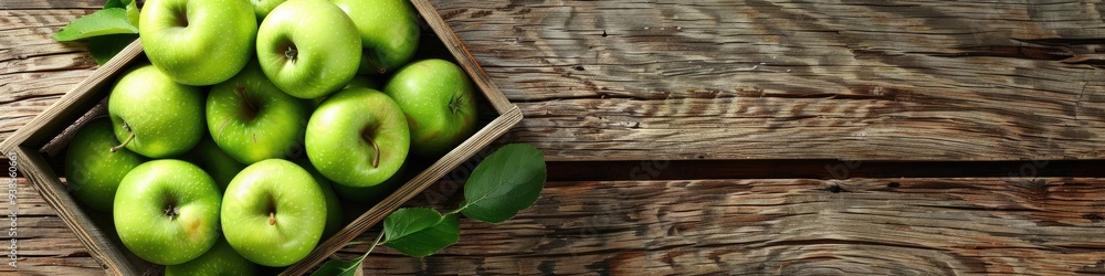 Poster flat lay of a wooden box containing fresh green apples on a rustic wooden surface with space for tex