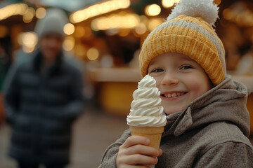 Fototapeta premium Photo of a happy boy with ice cream at a Christmas market on a winter day. It is snowing, with blurred people in the background and a bokeh effect. 