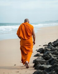  monk walking on a beach with rocks and water.