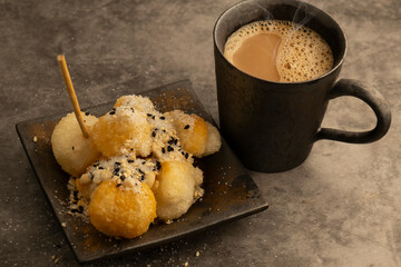 Hot coffee with Chinese style fried dough snacks sprinkled with sugar, nuts, and sesame.