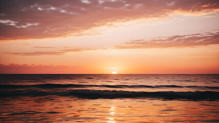 Obraz premium A serene sunset over a calm ocean with soft pink and orange hues