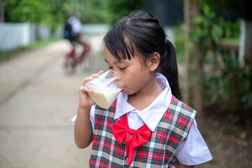 A young girl drinking milk from a glass