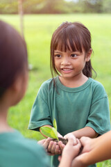 A young girl is holding a plant in her hand and smiling