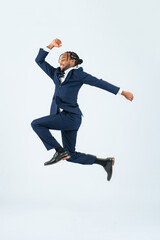 Full-body photo of a black male business person jumping in front of a white background