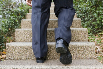 계단을 올라가는 정장 바지를 입은 남성의 다리, AI 생성
