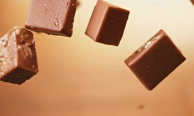 Chocolate Squares in Motion:  A mesmerizing image of smooth, rich chocolate squares suspended in mid-air, captured with a captivating blur.  The squares appear to be floating in a warm, inviting light
