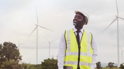 African engineer smile and using tablet with the wind turbine for inspect the operation of large...