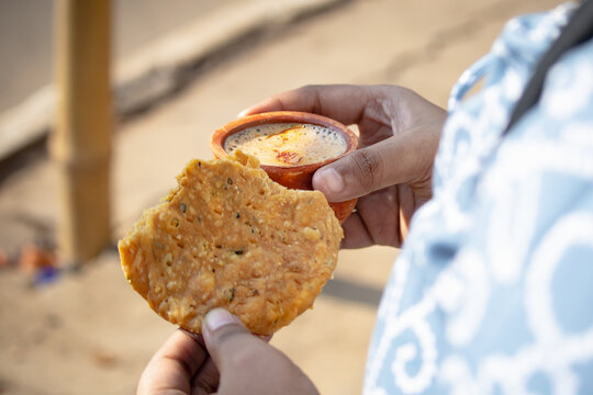 Mathri with hot tea in clay pot held in hand for eating in morning as traditional Indian breakfast. Mathri is a Rajasthani local snacks.