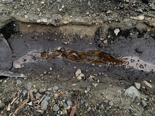 contaminated water with coal on coal yard area. A small stream of water flows through a gravel path, creating a natural drainage channel.