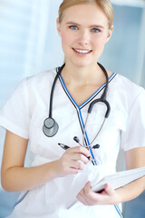 Portrait, nurse and woman with smile, notebook and healthcare with wellness, smile and career ambition. Face, person and medical with professional in uniform, documents and stethoscope in hospital