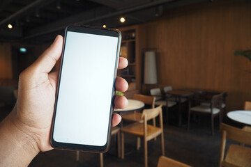 A hand holding a smartphone in a trendy cafe radiating a contemporary atmosphere