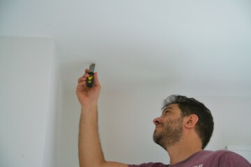 Domestic Wall Repair Tasks. Adult man holding a spatula to repair a damaged section of the wall