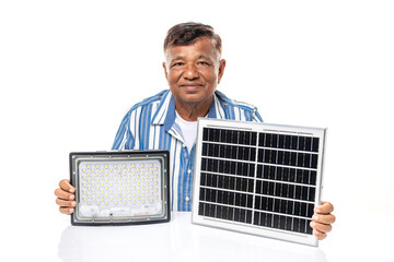 Senior Asian man smiling holding solar cell panel and spotlight LED isolated on white background,...