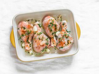 Cooking baked chicken legs with paprika, garlic and thyme on a light background, top view