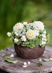 Flower arrangement with white dahlia, showy stonecrop flowers and snowberry branches in a rustic vase. Floristic or gardening concept. Selective focus. Copy space