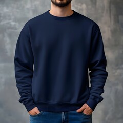 A young man is wearing a plain navy blue sweatshirt mockup, standing confidently against a textured gray background. 