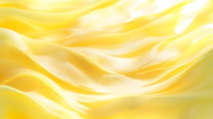 A close-up view of soft, flowing yellow satin fabric that creates a luxurious and elegant background. 