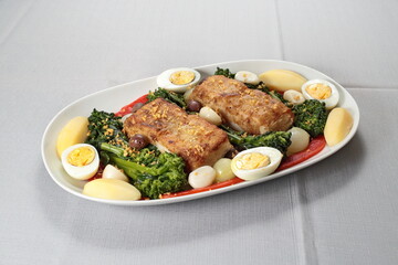 Portuguese cod with eggs, broccoli and peppers on a plate