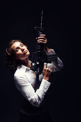 Woman, portrait and serious with rifle in studio for business security or company protection on black background. Female person, mafia or gun for corporate crime, corruption or white collar criminal