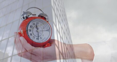 Holding red alarm clock, hand animation over building and sky background - Powered by Adobe