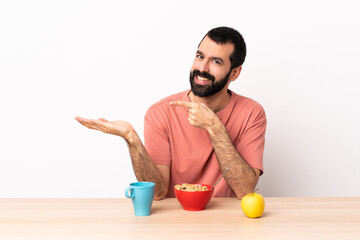 Caucasian man having breakfast in a table holding copyspace imaginary on the palm to insert an ad.