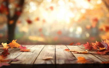 Selbstklebende Fototapeten Fallen leaves on wooden tabletop with autumn blurred background. Maple leaves with vibrant backlight from the setting sun. Cozy harvest season atmosphere  © Alena