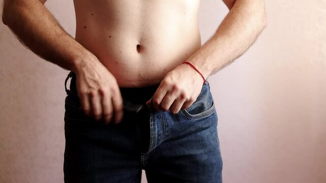 Man unbuttons and removes his jeans and pulls them down his legs
