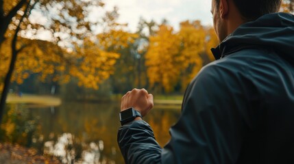 A fitness enthusiast using a smartwatch and fitness tracker while jogging in a park, with a scenic view of trees and a lake in the background, showcasing the importance of health and technology in