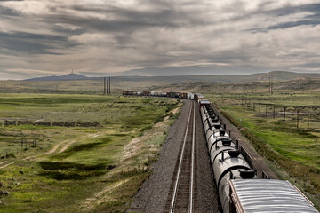 A long freight train trails off into the distance under stormy skies