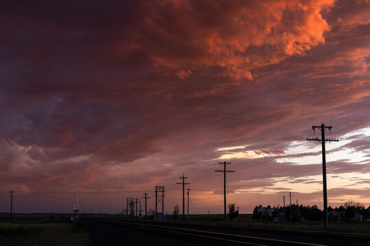 Dramatic cloudy skies at sunset over rural train tracks