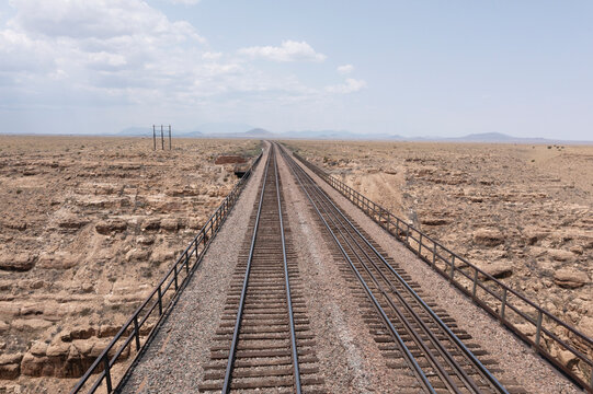 Parallel train tracks going over a bridge and into the desert