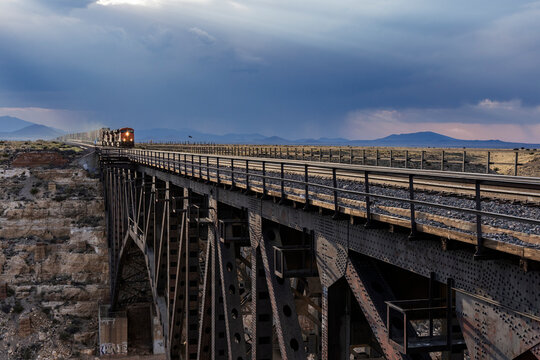 A distant train enters a long bridge from opposite end