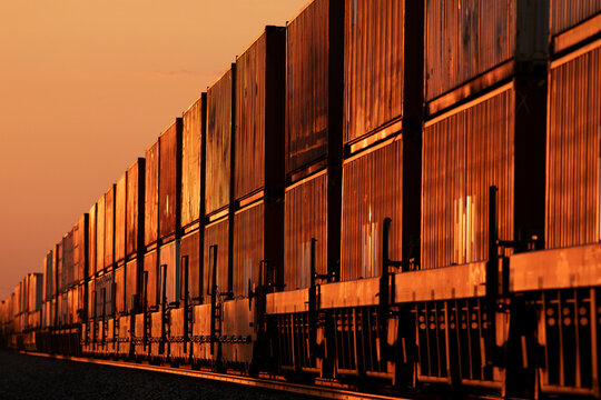 A long container stack train glowing in the amber sunset