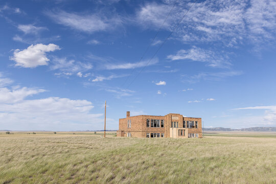 An abandoned school building standing in a field