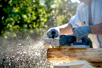 a carpenter works with an electric pipe on a sunny day