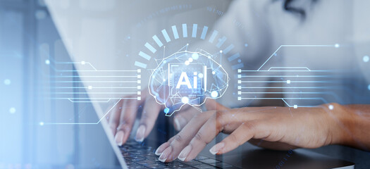 Hands typing on laptop with AI technology hologram overlay.