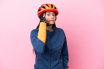 Teenager cyclist girl isolated on pink background thinking an idea