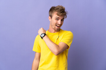 Young handsome blonde man isolated on purple background celebrating a victory