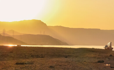 Sunset at Al Ain Al Sokhna, Suez, Egypt, with a truck driving along the beach. Mountains and soft...