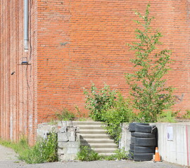 Obraz premium A concrete porch overgrown with grass and trees near a red brick wall