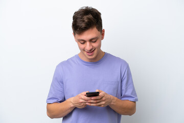Young handsome Brazilian man isolated on white background sending a message with the mobile