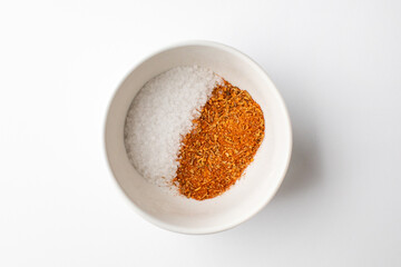 A white bowl containing an equal mix of salt and red spices, representing balance in cooking ingredients and flavors