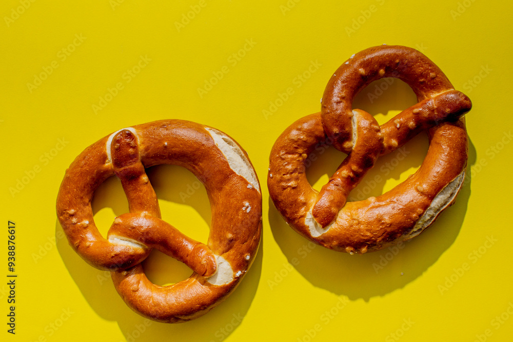 Wall mural two traditional german pretzels on a bright yellow background, perfect for oktoberfest celebrations 