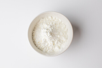 White powder in a bowl, zoomed in on a white background, commonly used for baking during Christmas holidays